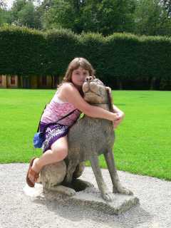 Ciska op een stenen hond in de tuin